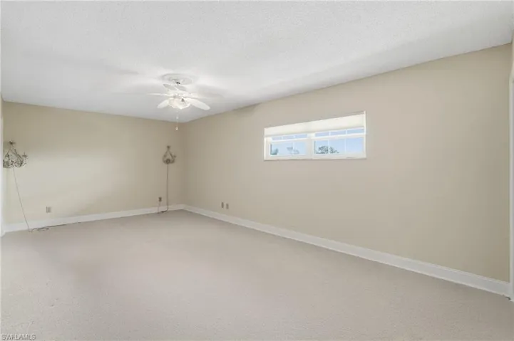 Carpeted spare room featuring a ceiling fan and a textured ceiling