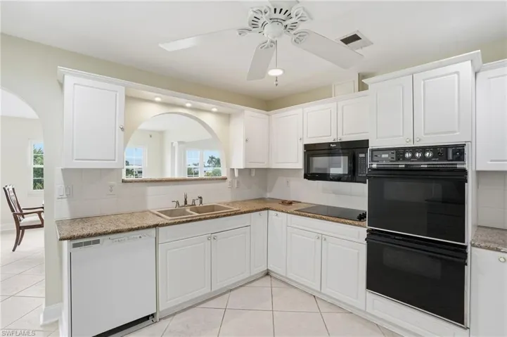Kitchen with black appliances, backsplash, white cabinetry, light tile patterned floors, and recessed lighting