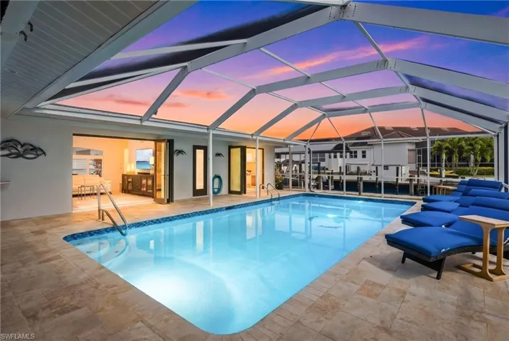 Pool at dusk featuring an outdoor pool, a patio, and a lanai