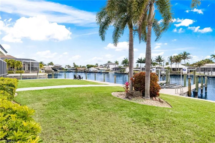 Dock area with a lawn, boat lift, a water view, and a residential view