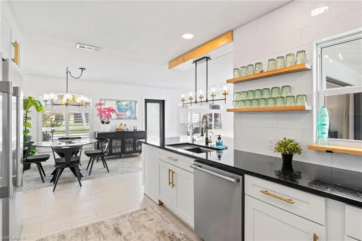 Kitchen featuring white cabinets, stainless steel appliances, hanging lights, and dark stone counters