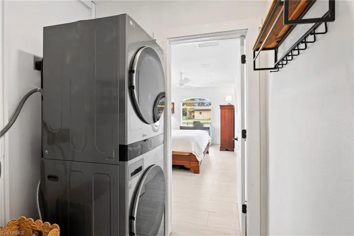 Laundry area with stacked washing machine and dryer and ceiling fan