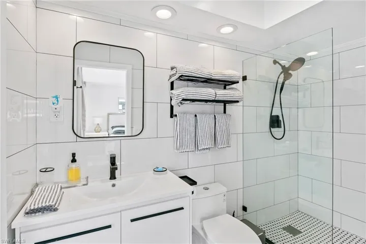 Full bath featuring vanity, a tile shower, tile walls, recessed lighting, and decorative backsplash