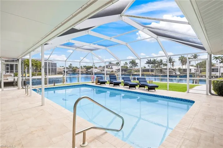 Swimming pool featuring a patio area, a lanai, a sunroom, a lawn, and a water view