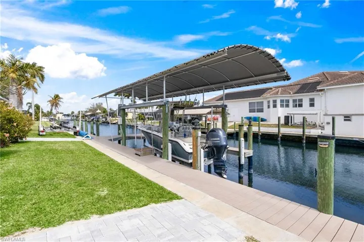 Dock with a lawn, boat lift, a water view, and a residential view