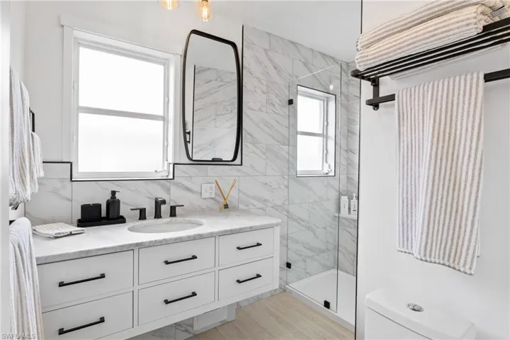 Bathroom featuring vanity and a marble finish shower