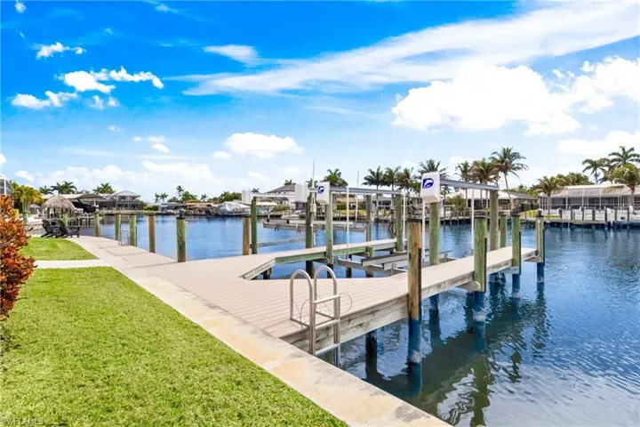 Dock with a water view, boat lift, and a yard