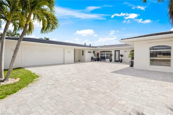 View of front facade featuring driveway, stucco siding, an attached garage, and a tile roof