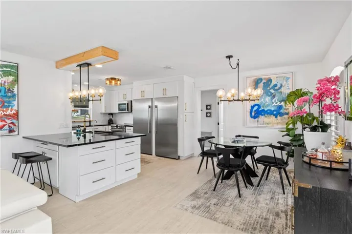 Kitchen with a chandelier, white cabinets, stainless steel appliances, a breakfast bar, and light wood-style floors