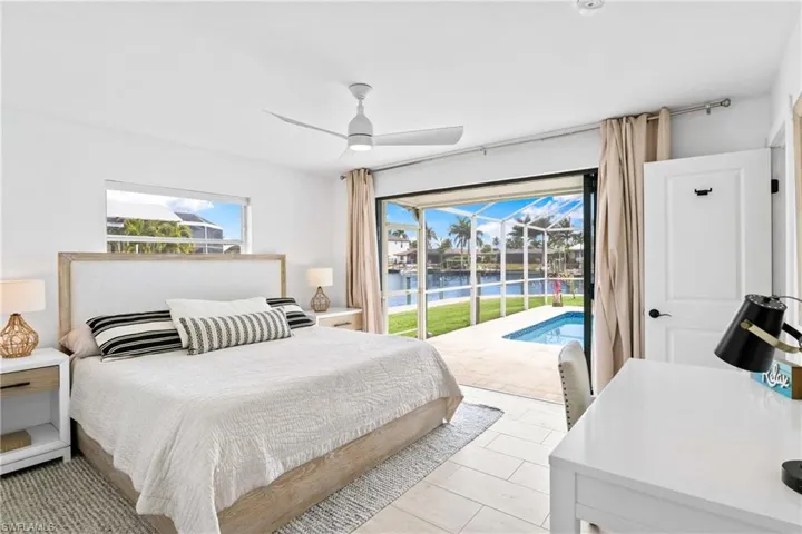 Bedroom with a water view, a sunroom, access to exterior, and ceiling fan