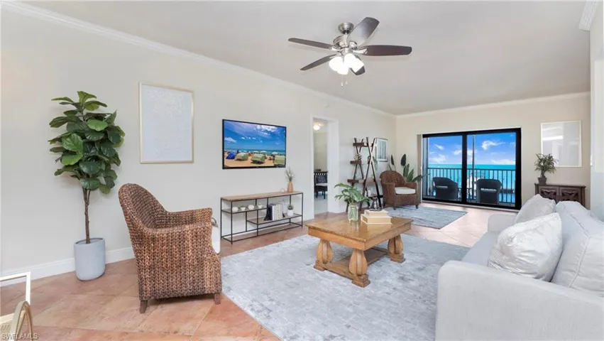Living area featuring light tile patterned flooring, ornamental molding, and a ceiling fan
