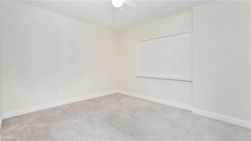 Carpeted empty room featuring baseboards and ceiling fan