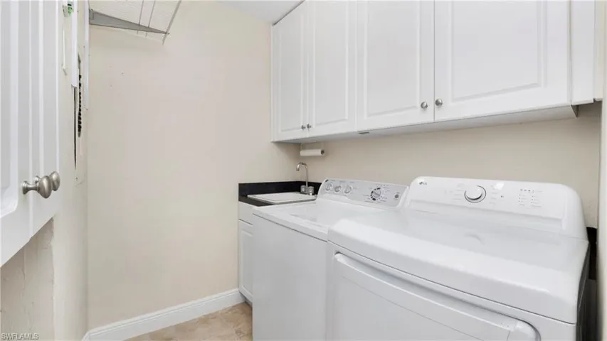 Washroom with cabinet space and washing machine and clothes dryer