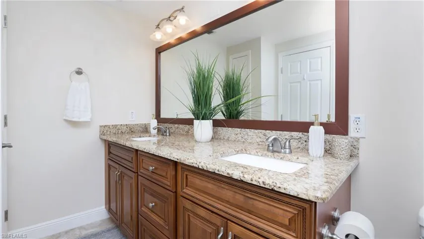 Full bath featuring double vanity and baseboards