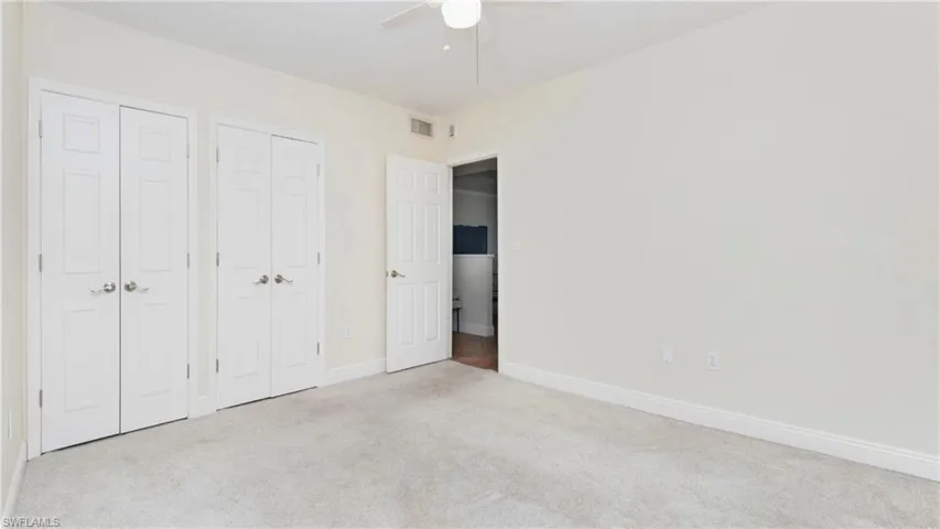 Unfurnished bedroom with carpet, multiple closets, and a ceiling fan