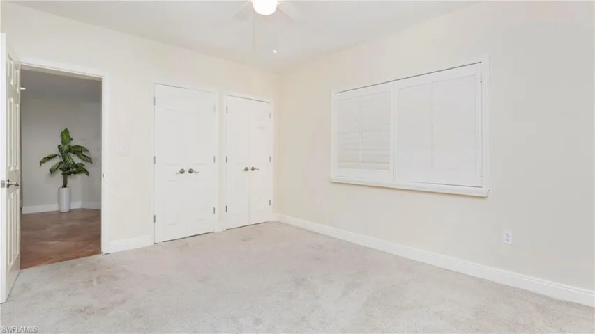 Unfurnished bedroom with two closets, carpet flooring, and a ceiling fan