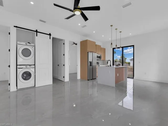Kitchen featuring a barn door, ceiling fan, a kitchen island with sink, and pendant lighting