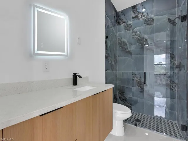 Full bath featuring vanity and a marble finish shower