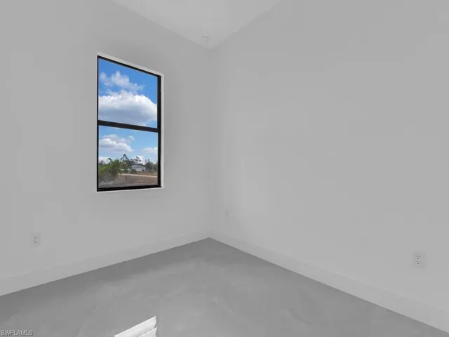 Spare room featuring baseboards and finished concrete flooring