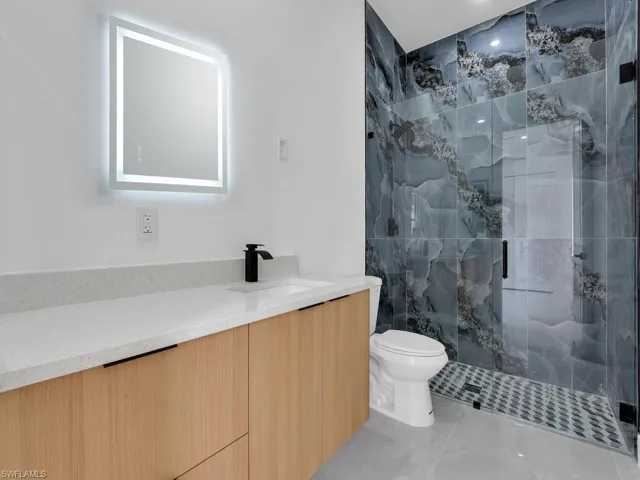 Bathroom featuring vanity, a marble finish shower, and light tile patterned floors