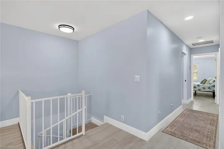Hallway with an upstairs landing and light wood-type flooring