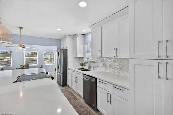 Kitchen with white cabinets, tasteful backsplash, stainless steel appliances, and hanging light fixtures