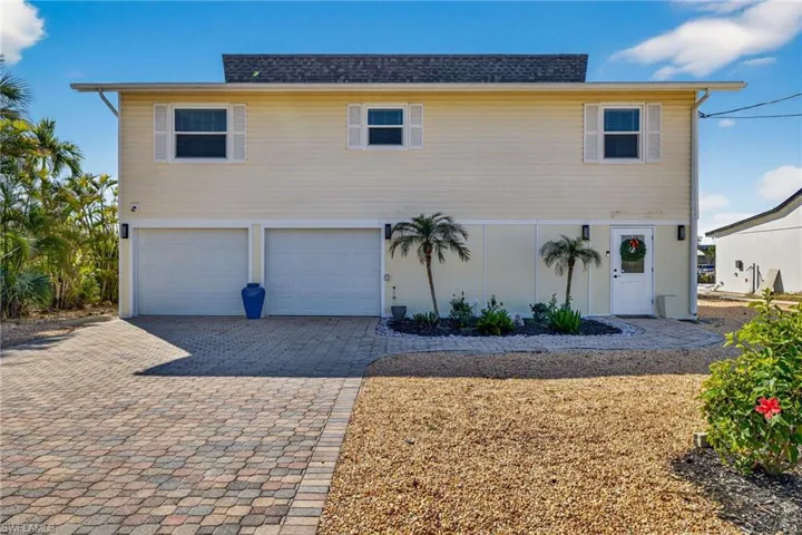 View of front of house with a garage, driveway, and a shingled roof