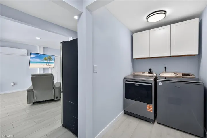 Laundry area with wood finish floors, cabinet space, separate washer and dryer, and recessed lighting