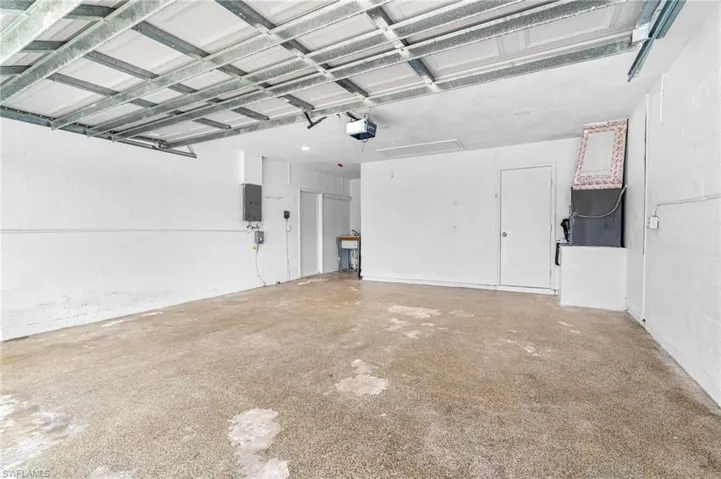 Garage with concrete block wall, A/C wall unit, and electric panel