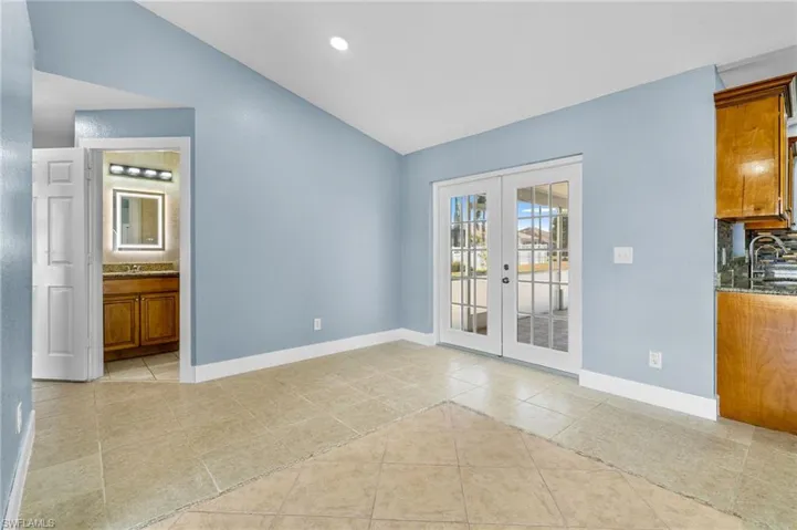 Unfurnished dining area featuring french doors, lofted ceiling, light tile patterned floors, and recessed lighting