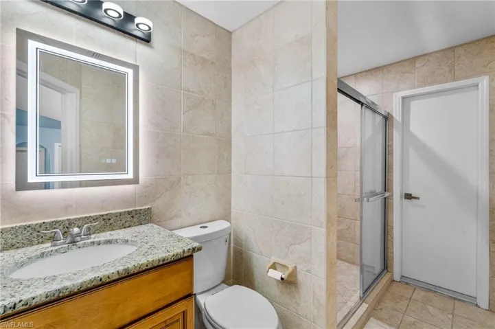 Bathroom with tile walls, a stall shower, and vanity