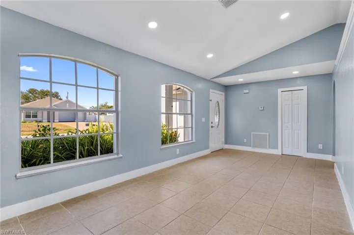 Spare room featuring vaulted ceiling, light tile patterned flooring, and recessed lighting