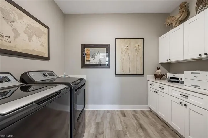 Laundry room with cabinets, light hardwood / wood-style floors, and washer and dryer