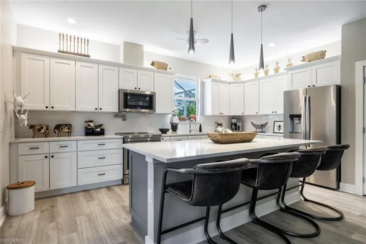 Kitchen featuring a breakfast bar area, a center island, hanging light fixtures, stainless steel appliances, Pot filler above the range and a beautiful pantry!
