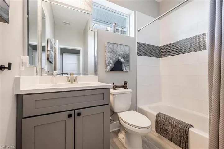 Guest Full bathroom featuring shower / bathtub combination with curtain, vanity, hardwood / wood-style flooring, and toilet
