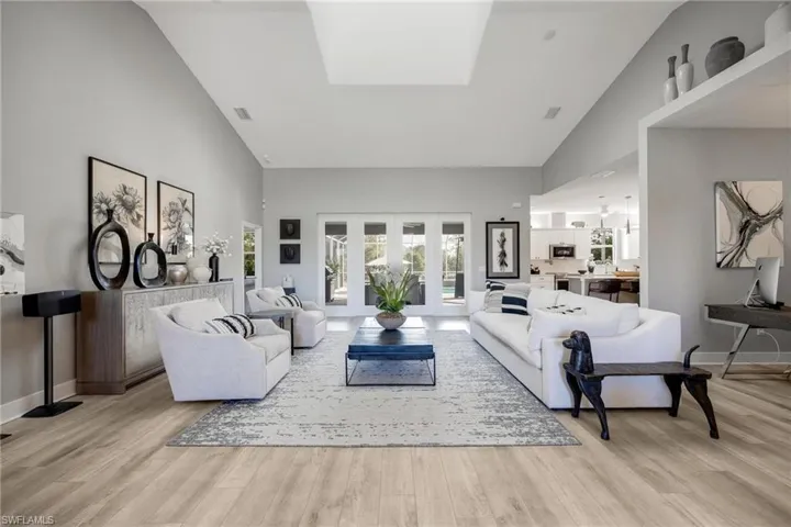 Living room with high vaulted ceiling and light hardwood / LVP wood-style flooring