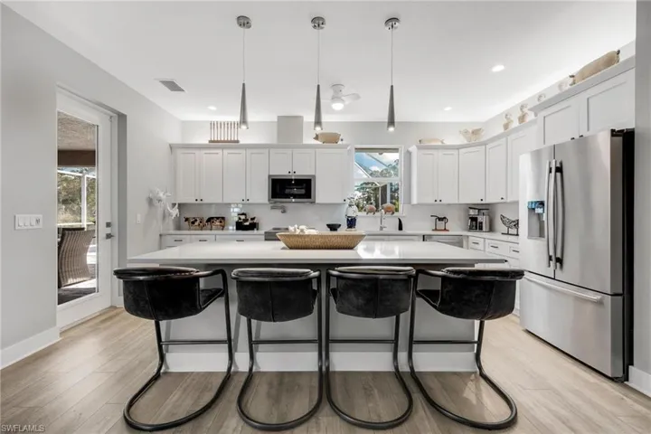 Kitchen with tasteful backsplash, a center island, hanging pendant light fixtures, and Jenn Aire appliances with stainless steel finishes