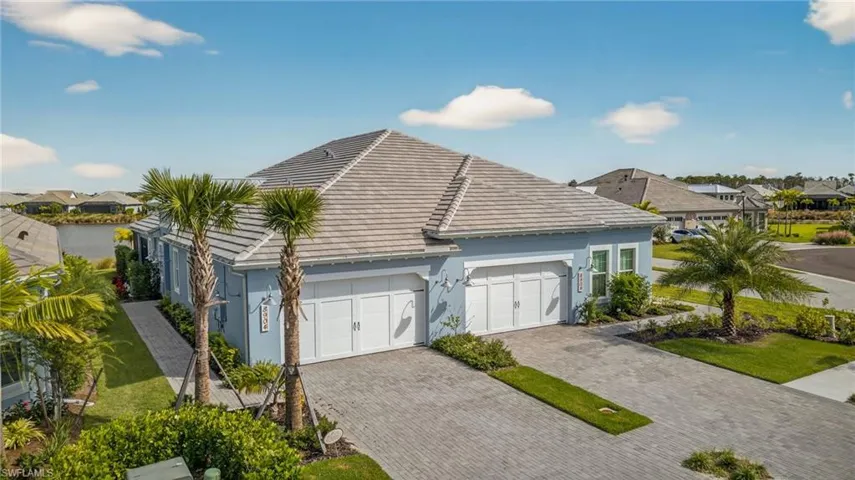 View of side of property with a tile roof, decorative driveway, stucco siding, and a residential view