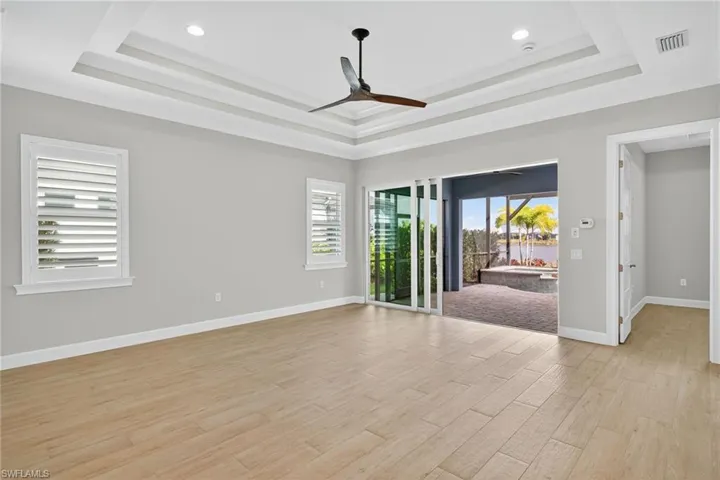 Unfurnished room featuring light wood-type flooring, a tray ceiling, a ceiling fan, and recessed lighting