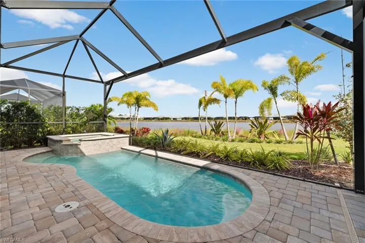 View of swimming pool with a lanai, a water view, a patio area, a sunroom, and a pool with connected hot tub