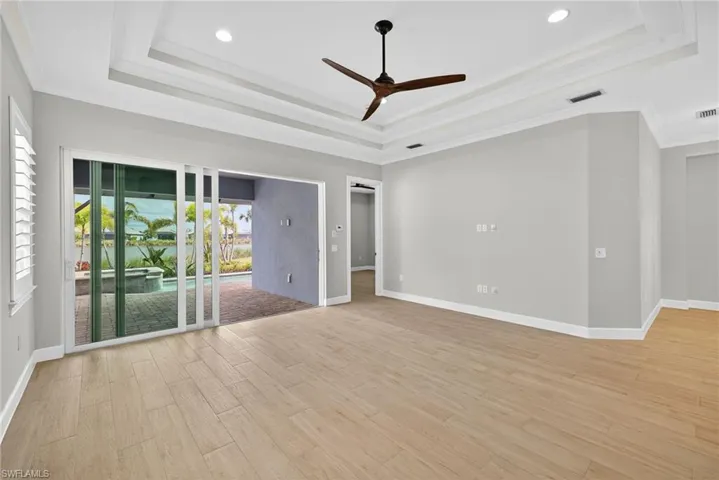 Spare room featuring a raised ceiling, light wood-style flooring, ceiling fan, ornamental molding, and recessed lighting