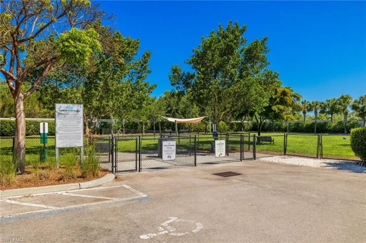 View of community with a gate, uncovered parking, and view of wooded area
