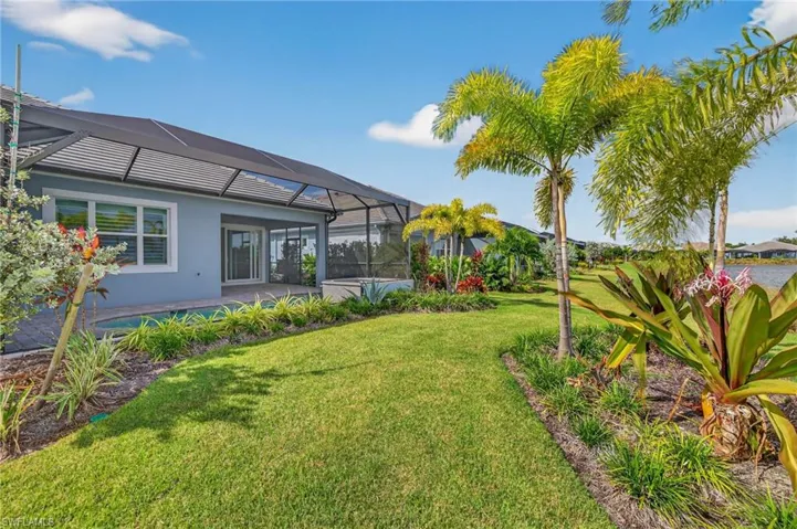 View of green lawn featuring a lanai, a patio, and a sunroom
