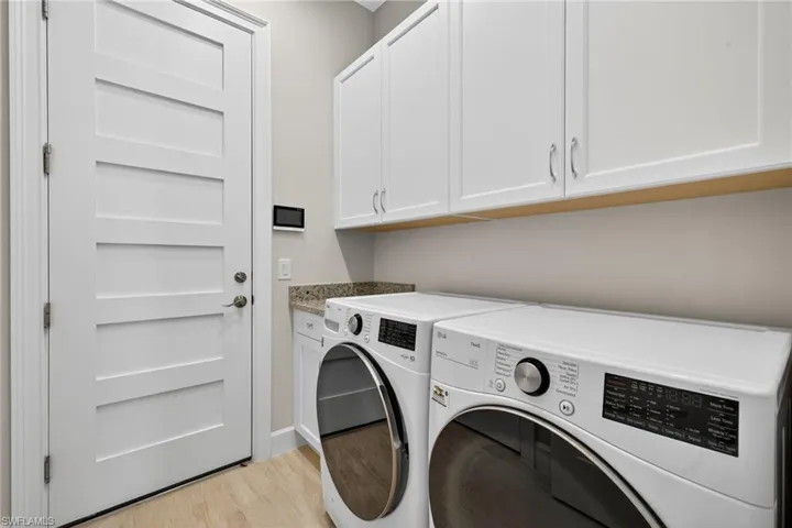 Laundry room with light wood-style flooring, washer and dryer, and cabinet space