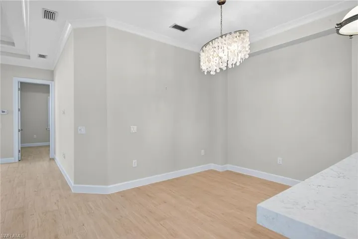 Unfurnished dining area with light wood-type flooring, ornamental molding, and a chandelier