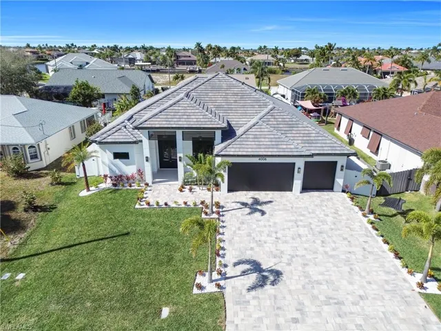 View of front facade with a tiled roof, decorative driveway, a front lawn, a garage, and a residential view