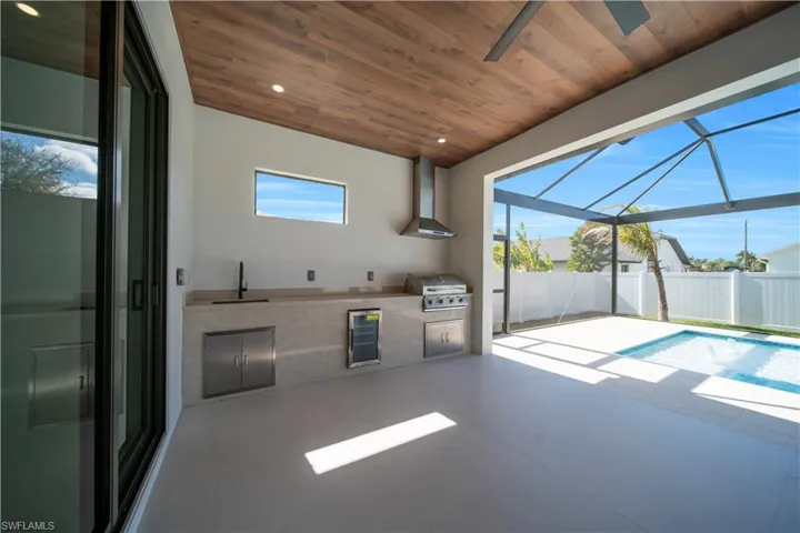 View of patio with a sunroom, a lanai, an outdoor kitchen, and beverage cooler