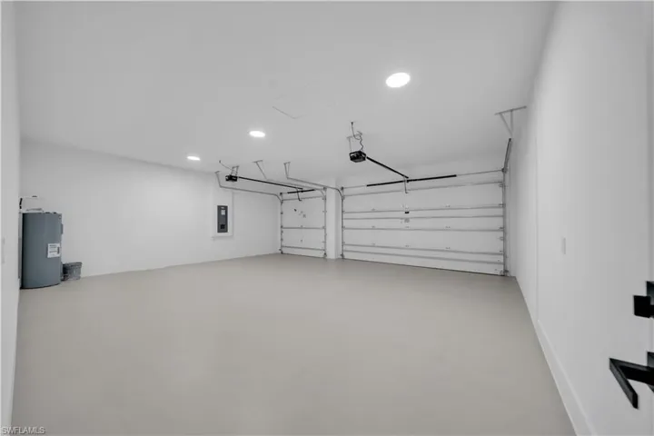 Garage with water heater, recessed lighting, and electric panel