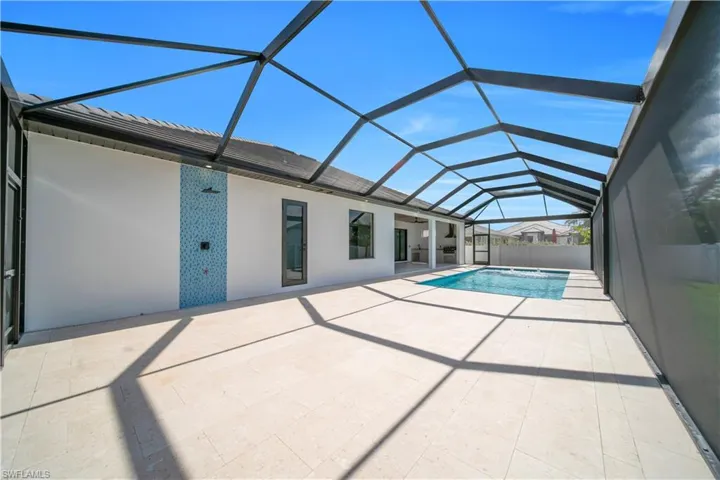 View of swimming pool featuring a sunroom, glass enclosure, patio surround, and a hot tub