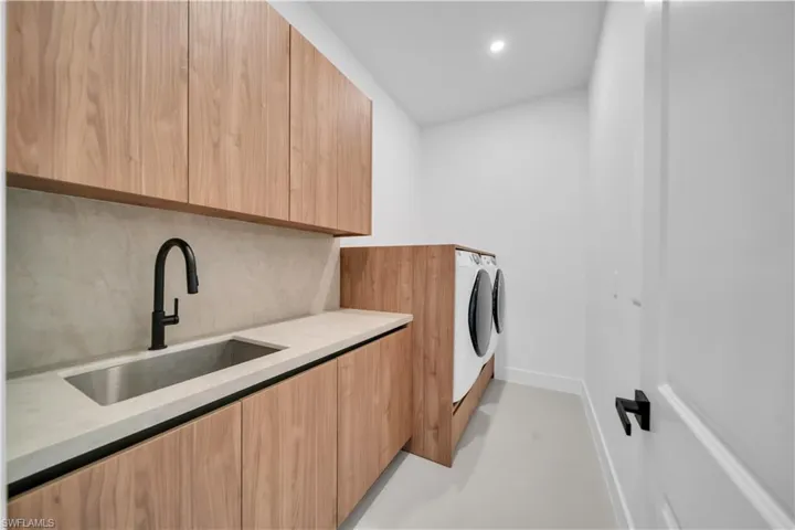 Laundry room with concrete flooring, cabinet space, washer and dryer, and recessed lighting